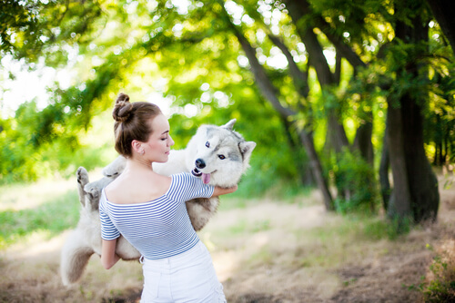 Nainen kantaa koiraa